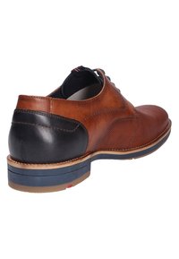 Bruine leren schoen met een gestructureerde afwerking, zwarte hakaccenten, blauwe zool en contrasterende stiksels. Vetersluiting.