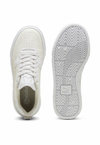 Vita sportskor med en slät syntetisk ovandel, perforerade detaljer, platta snören och strukturerade gummisulor med ett zigzag-mönster.