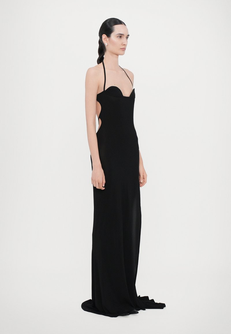 Black evening gown with a fitted silhouette, halter neckline, side cutouts, and delicate floor-length fabric. Smooth texture and minimal design.