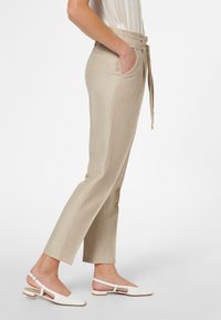 Beige, skräddarsydda byxor med vertikala ränder, hög midja och sidofickor. Kombineras med vita slingback-skor med en minimalistisk design.