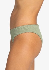 Texturované zelené bikiny s nízkým pasem, které mají hladký elastický pás a bezšvové okraje pro pohodlí.