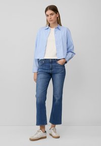 Chemise rayée bleu clair et blanche avec fermeture à bouton, associée à un jean bleu foncé et des baskets beiges avec une semelle en caoutchouc. Texture de tissu lisse.