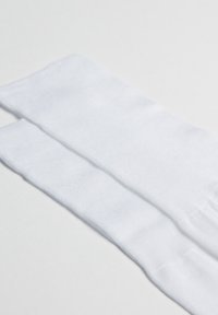 White cotton socks positioned side by side, featuring a smooth texture and a simple, seamless design without patterns or accents.