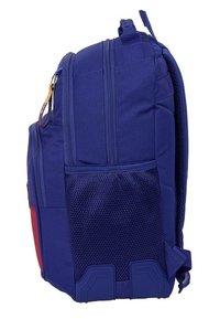 Niebieski plecak z tkaniny z siatkową kieszenią, o wyważonym kształcie, z przodu kieszeń do przechowywania, górny uchwyt oraz trwały spód zapewniający stabilność.