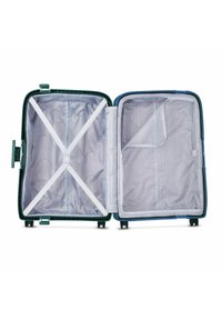 Valise rigide vide ouverte avec compartiment en maille zippé sur le côté et sangles croisées réglables à l'intérieur, présentée sur un fond blanc.