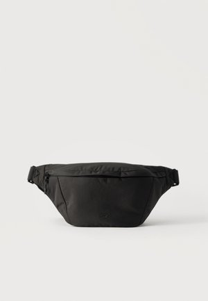 Svart midjeveske i stoff med frontlomme med glidelås og justerbar stropp, vist på hvit bakgrunn.