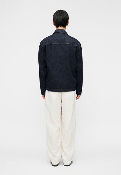 Σκούρο τζιν μπουφάν με γιακά με κουμπιά, πίσω πέτα, και μακριά μανίκια, συνδυασμένο με άνετο λευκό παντελόνι. Ομαλή υφή και κλασικός σχεδιασμός.