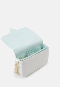 Vit läderväska med mintgrön mockafodring, rektangulär form, gyllene detaljer och zippered ficka för förvaring.