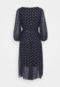 Robe midi bleu marine avec manches bouffantes transparentes, motif goutte argenté, taille cintrée et jupe fluide, vue de dos sur fond blanc.