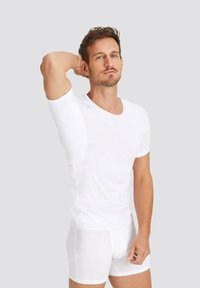 White short-sleeve fitted t-shirt with a deep V-neck and an integrated sleeve feature, paired with white boxer shorts. Smooth texture.