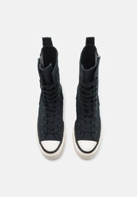 Baskets montantes noires avec fermeture à lacets à l'avant, en toile, bout en caoutchouc blanc, et détails cousus le long de la semelle.