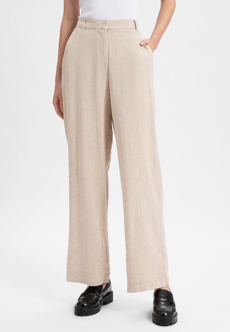Beige wide-leg trousers with a textured fabric, featuring a mid-rise waist and side pockets, paired with black platform loafers.