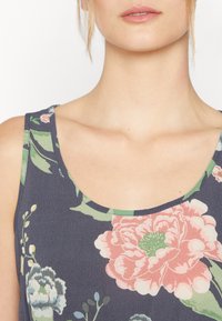 Top floral com fundo azul-marinho, estampa de flores rosa e verde, decote redondo e textura de tecido suave.