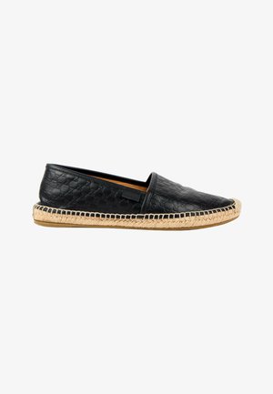 Espadrille en cuir noir à enfiler avec motif embossé, semelle en jute tissée naturelle et semelle en caoutchouc, vue de profil sur fond blanc.