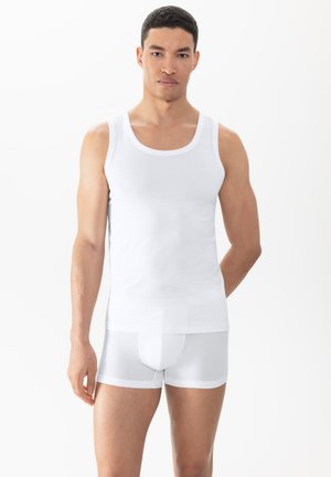 Débardeur blanc avec des bretelles larges, texture lisse. Assorti à des boxers moulants blancs avec un motif en maille. Design simple et minimaliste.