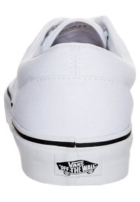 Witte canvas lage sneakers met zwarte rubberen buitenzool, ronde neus en logo op de hak. Voorzien van een eenvoudig vetersysteem en gestikte accenten.