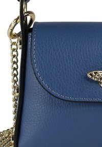 Blauwe leren handtas met een gestructureerde afwerking, gouden hardware, een kettingriem en een decoratieve sluiting op de klep.