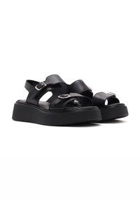 Black leather platform sandals with adjustable straps and silver buckles. Features open toe design and textured sole for grip.