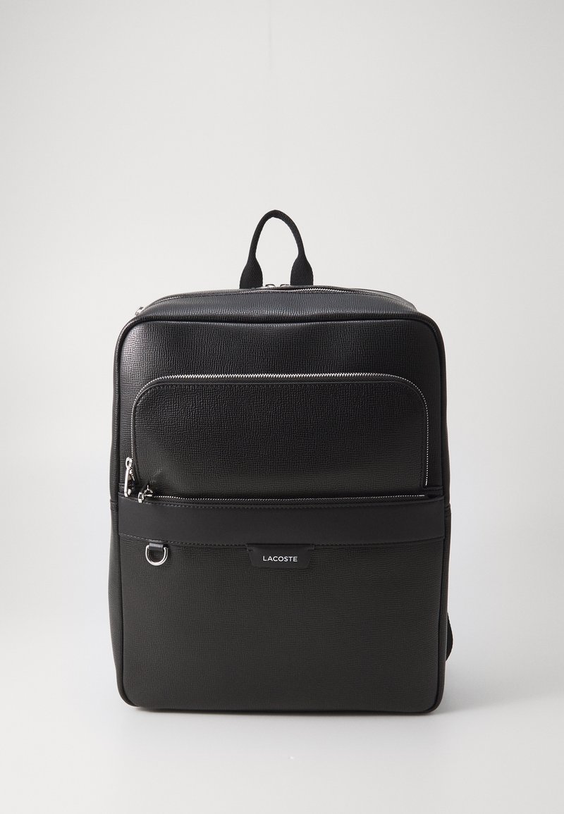 Mochila preta texturizada com um bolso frontal com fecho, alça superior e detalhe do logotipo. Apresenta zíperes suaves e um design elegante e estruturado.