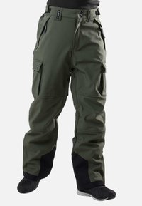 Groene cargo pants met zwarte verstevigingen bij de enkels, meerdere rits- en knoopzakken, gedragen met zwarte schoenen en een zwart shirt.
