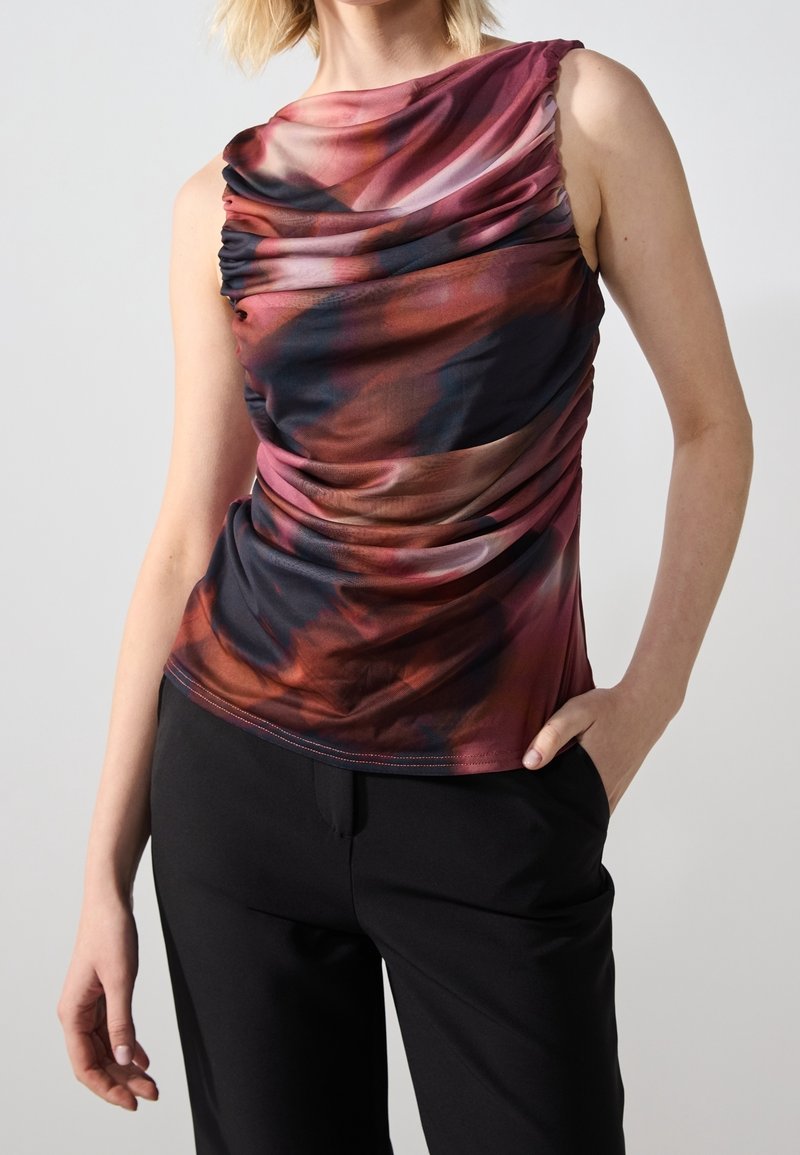 Des hauts avec un design drapé multicolore dans des teintes de rouge, noir et violet, fabriqués en matériau doux avec une silhouette ajustée.
