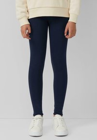 Navy leggings van rekbaar materiaal, met een gladde textuur en een aansluitend ontwerp, gecombineerd met witte sneakers voor contrast.