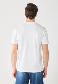 White short-sleeve t-shirt with a round neckline, made from soft cotton fabric. Simple design, no patterns or accents visible.
