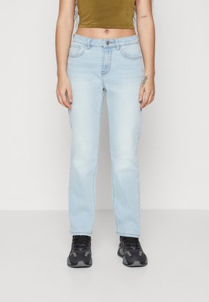 Light blue jeans made of denim, featuring a straight cut, five pockets, and a button-fly closure. Worn with black athletic shoes.