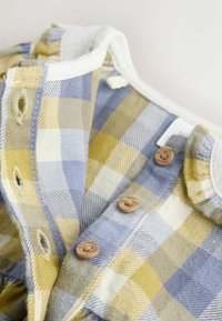 Kockás ing kék és sárga plaid mintával, gombos záródással, puha pamut anyagból, valamint fehér színű, finom textúrájú gallérral.