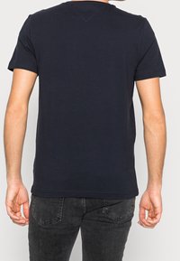 Marineblå T-shirt med kortærme lavet af bomuld, med rund halsudskæring og en afslappet pasform, parret med mørkegrå jeans.