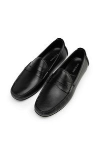 Mocasines de cuero negro con un acabado texturizado, punta redondeada y costuras decorativas. Presenta una banda decorativa a lo largo del empeine. Suela plana.