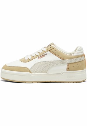 Baskets basses Puma blanches et beiges avec des accents en daim, fermeture à lacets et détail de bande latérale texturée.