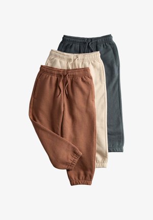 Tre par joggingbukser i fleece i brun, creme og mørkegrå med elastiske taljebånd, snoretræk, sidelommer og manchetter ved anklerne.