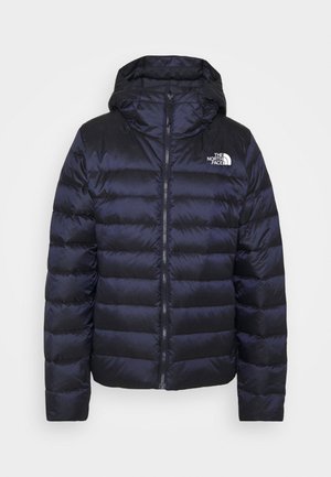 Granatowa kurtka puchowa z kapturem. Posiada pikowane sekcje, zamek błyskawiczny z przodu oraz logo na lewej piersi. Gładka, błyszcząca tekstura.