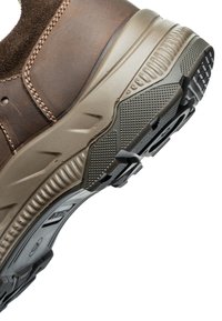 Brauner Lederschuh mit strukturierter dunkler Sohle, ausgestattet mit einer gepolsterten beigen Zwischensohle, detaillierten Nähten und einem robusten Profil.