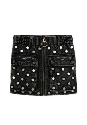 Mini falda vaquera negra con tachuelas plateadas, dos bolsillos frontales con solapa, cintura elástica y cremallera central con un tirador circular.