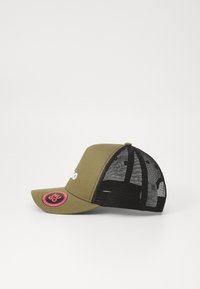 Olivgrüne Kappe mit schwarzem Netzrücken, gebogenem Schirm, weißem Logo auf der Vorderseite und einem runden rosa Akzent-Patch an der Seite.