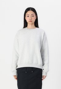 Lichtgrijze sweatshirt met een ronde hals, verlaagde schouders en geribbelde mouwen. Heeft een subtiele logo op de borst en een relaxte pasvorm.