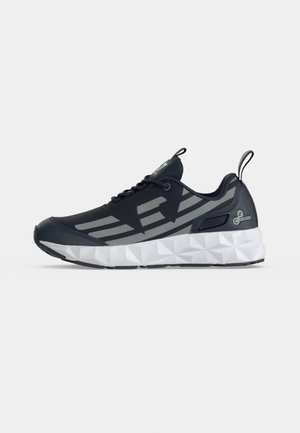 Chaussure de sport noire et grise avec semelle blanche texturée, fermeture à lacets à l'avant et languettes sur la languette et le talon, vue de côté gauche.