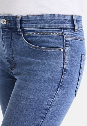 Blue denim jeans feature a slim fit with a smooth texture, five-pocket design, and contrasting stitching on the seams.