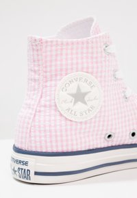 Růžové kostkované vysoké tenisky s bílými otvory a tkaničkami, se zaobleným logem Converse a námořnickou gumovou podrážkou.
