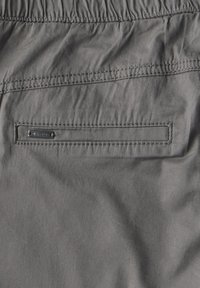 Grijze shorts met een geregenelastische tailleband, voorzien van een vlakke achterzak met een subtiel label en een zachte, lichtgewicht stoftextuur.