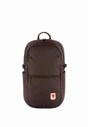Mochila marrón oscuro con bolsillos delanteros y laterales con cremallera, asa superior y un pequeño parche con logo rojo en la parte inferior delantera.