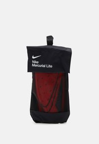 Nike Mercurial Lite kott musta värvi, punase sisuga, millel on rullitav disain ja käepide kandmiseks.