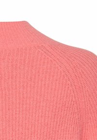 Strickpullover in leuchtendem Pink mit gerippter Textur, featuring einem hohen Kragen und Raglanärmeln, das ein weiches und komfortables Design betont.