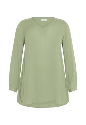 Långärmad blus med V-ringning i mjukt, ljusgrönt tyg med en texturerad yta och en rundad nederkant. Har lätt puffade ärmar.