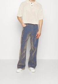 Polo tričko z bavlny v bílé barvě s krátkým rukávem a texturovaným vzorem. Modré džíny z denimu se zesvětleným, opotřebovaným vzorem a rovný střih.