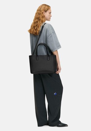 Schwarze strukturierte Tragetasche mit doppelten oberen Griffen und einem abnehmbaren Schultergurt, ausgestattet mit einer strukturierten Oberfläche und minimalistischem Design.