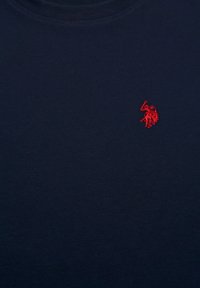 Navy blue fabric with a small red embroidered logo of a polo player on a horse, located near the upper right chest area.