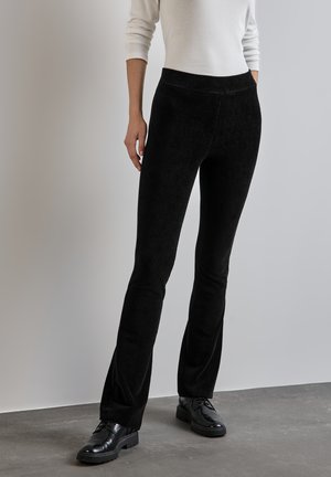 Pantaloni in cotone a coste neri con vita liscia, caratterizzati da una texture a righe verticali e una vestibilità rilassata fino alla caviglia.
